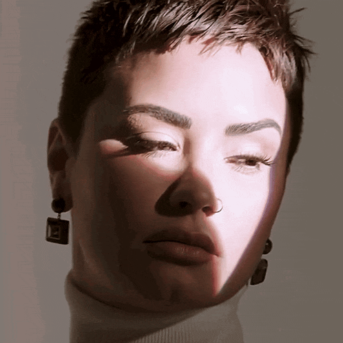 a close up of a woman 's face with a turtleneck and earrings