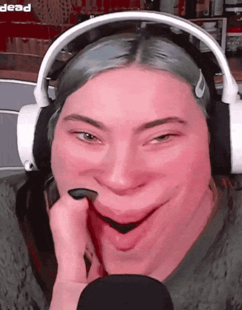 a woman wearing headphones is making a funny face with the word dead in the background
