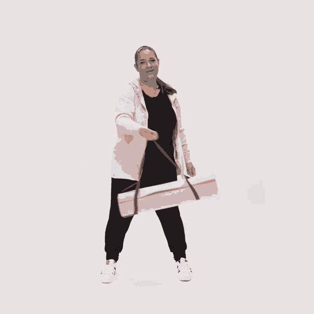 a woman is holding a pink yoga mat in her hand