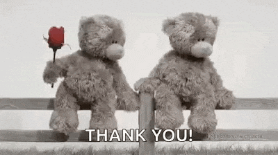 two teddy bears are sitting on a fence holding hands .