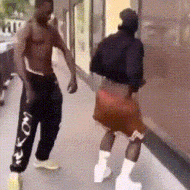 a man without a shirt is standing next to a woman in shorts and boots .