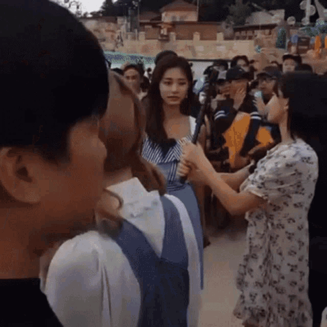 a woman is holding a microphone while talking to a man in a crowd .