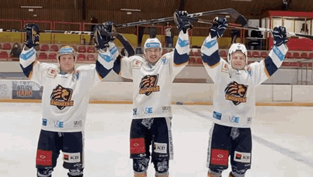 three ice hockey players are holding their sticks up in the air while wearing jerseys that say eagles