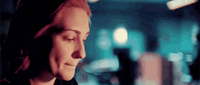 a close up of a woman 's face in a dark room with a blurred background .
