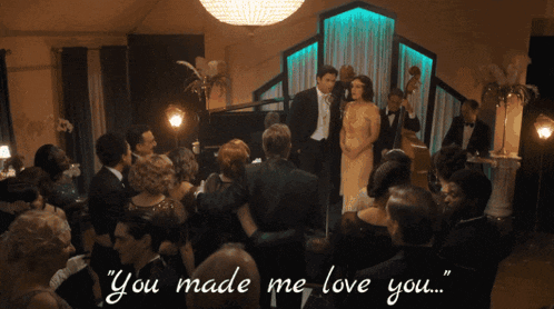 a man in a tuxedo stands in front of a crowd with the words " you made me love you " written on the bottom