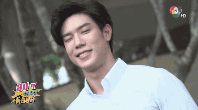 a man in a white shirt is smiling in front of a tv screen that says hd