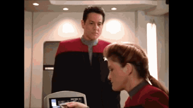 a man and a woman are looking at a screen that says ' star trek ' on it ..