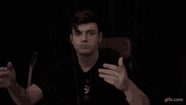 a young man is making a peace sign with his hands in front of a black background .