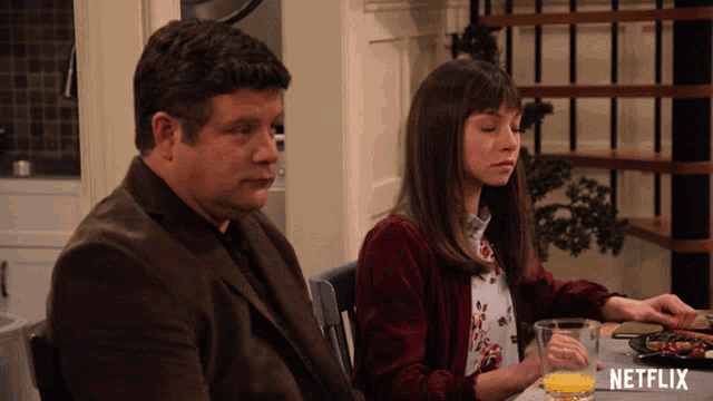 a man and a woman are sitting at a table with a netflix logo on the table