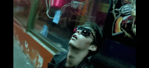 a man wearing sunglasses and a leather jacket is laying on the ground