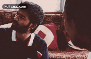 a couple of men sitting on a couch with a kulfyapp.com logo on the bottom right