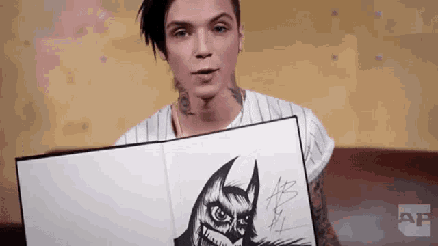 a man is holding a book with a drawing of a batman .