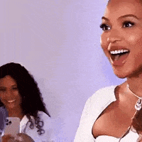 a woman is smiling with her tongue out while another woman holds a cell phone .