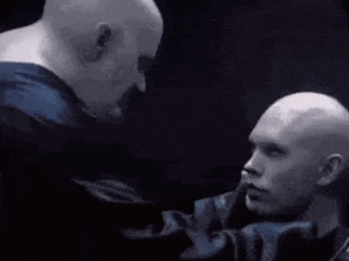 two bald men are looking at each other in a dark room .
