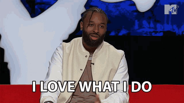 a man sitting on a red couch with the words i love what i do above him