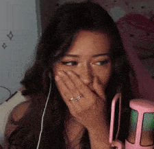 a woman with a ring on her finger covering her mouth with her hand