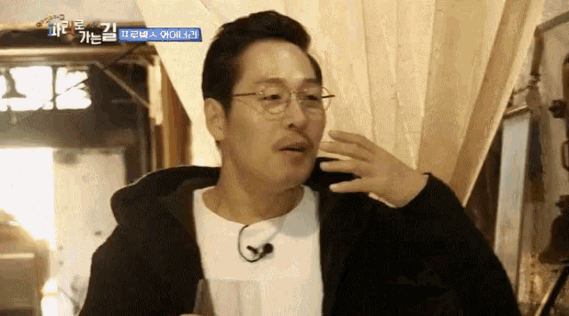 a man wearing glasses holds a glass of wine