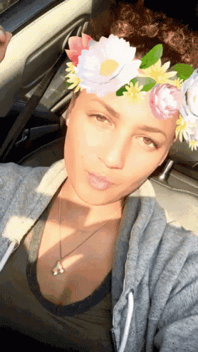 a woman wearing a flower crown is taking a selfie