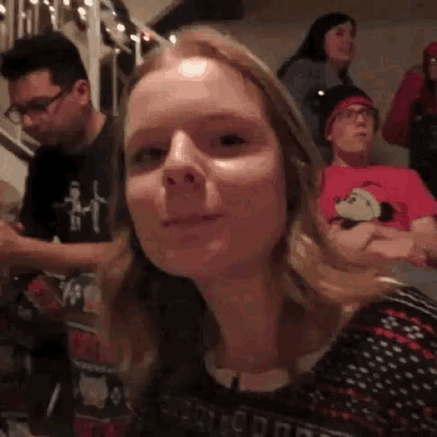 a woman is making a funny face while sitting at a table with a group of people .