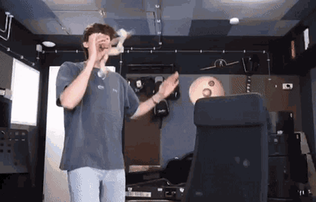 a man in a gray shirt is playing a trumpet in a room .
