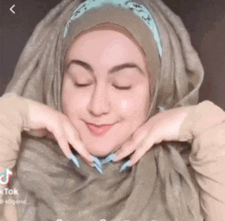 a woman wearing a hijab and a headband is smiling with her eyes closed