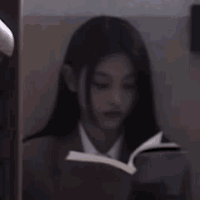 a girl in a suit and tie is reading a book