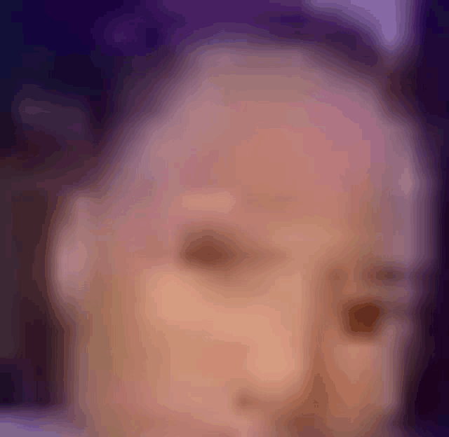 a blurry picture of a person 's face with purple background .