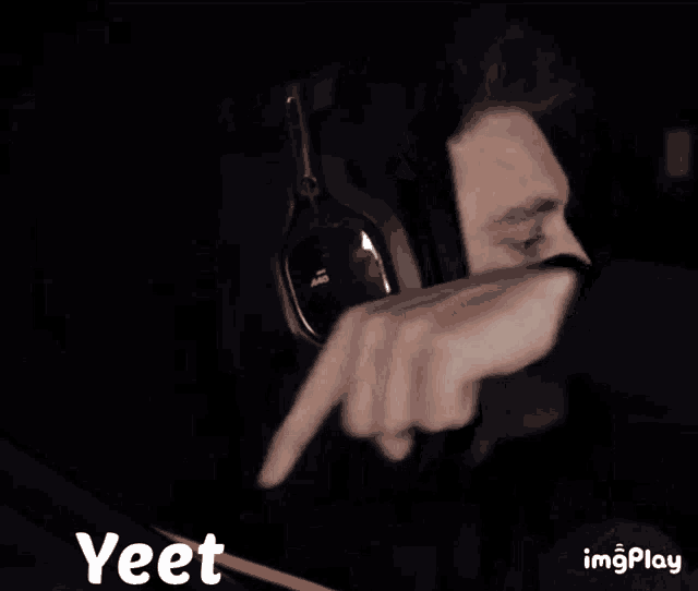a man wearing headphones and a hoodie is making a face .