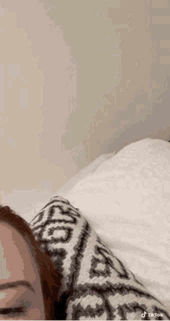 a woman is laying on a bed with a sweater on .