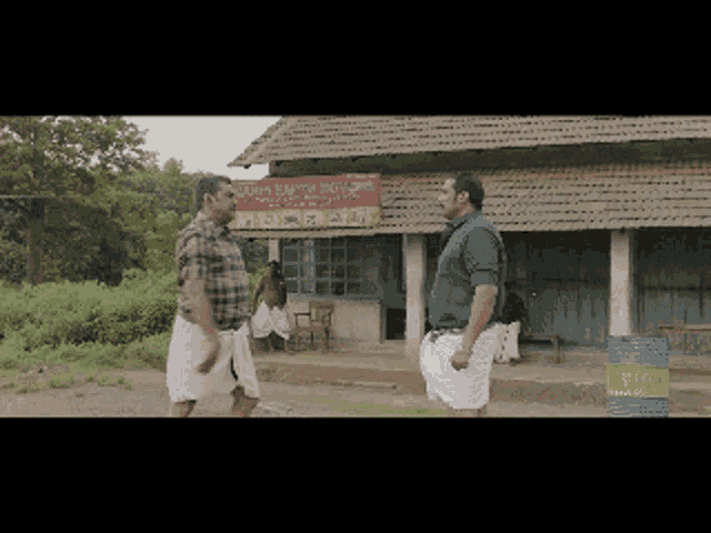 two men standing in front of a building with a sign that says ' chennai bakery shop '