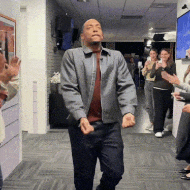 a man in a grey jacket is dancing in an office