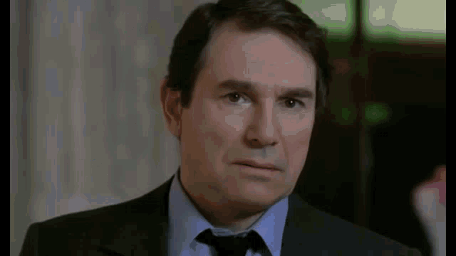a man in a suit and tie is making a serious face .