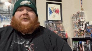 a man with a beard wearing a green hat and a black shirt with the word wrestlers on it
