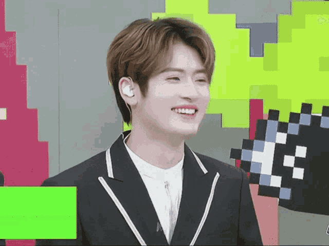 a young man wearing a suit and ear buds is smiling