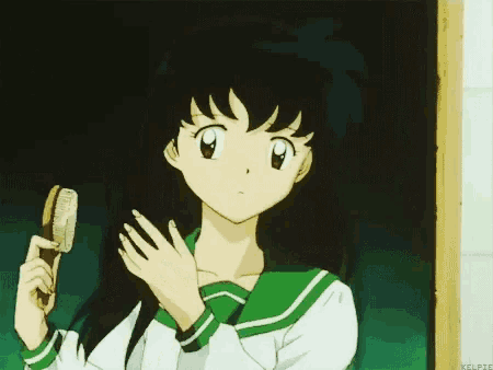 a girl in a green and white school uniform is brushing her hair .