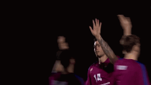 a man raising his hand in the air in front of a screen that says ' fcb ' on it