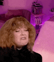 a woman with red hair is making a funny face in front of a pink wall .