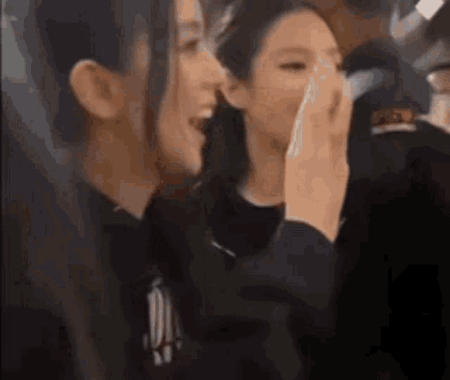 a couple of women are sitting next to each other and laughing .