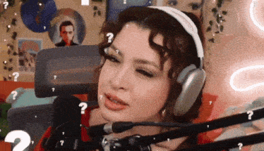 a woman wearing headphones is sitting in front of a microphone with question marks around her head