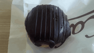 a close up of a chocolate donut on a piece of paper with the letters o on it