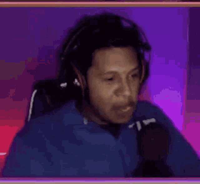 a man wearing headphones is laughing while sitting in a chair in front of a microphone .