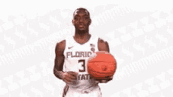 a florida state basketball player is spinning a basketball on his finger .