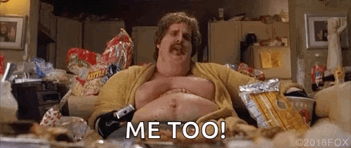 a very fat man is sitting on a couch in a messy kitchen eating chips .
