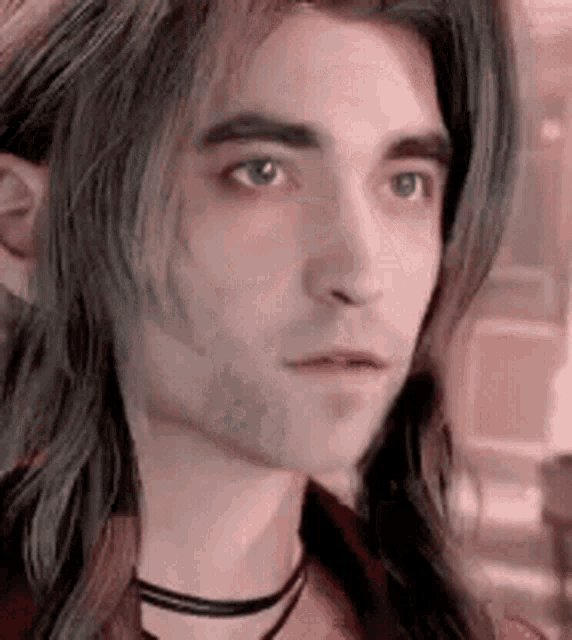 a close up of a man with long hair and a choker .
