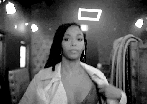 a black and white photo of a woman taking off her jacket and bra .