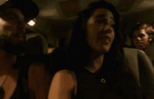 a woman is sitting in the back seat of a car with a man behind her .
