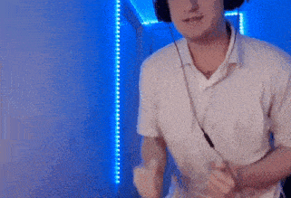 a man wearing headphones and a white shirt is dancing in front of a blue wall .