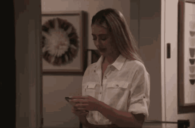 a woman in a white shirt is using her phone
