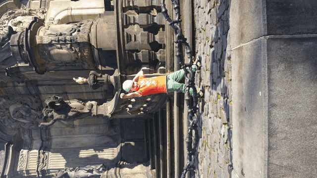 a person laying on a stone wall wearing a red shirt that says ' a ' on it