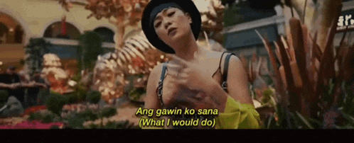 a woman in a black hat is standing in front of a skeleton and says ang gawin ko sana